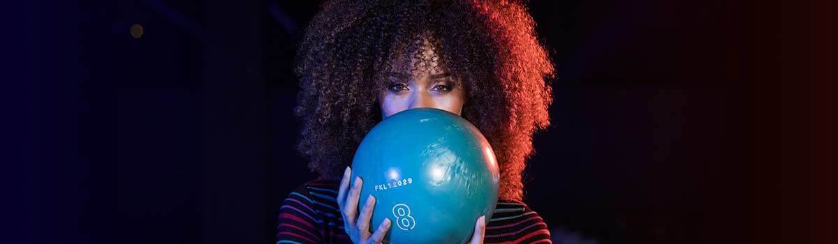 Woman with bowling ball in front of her face