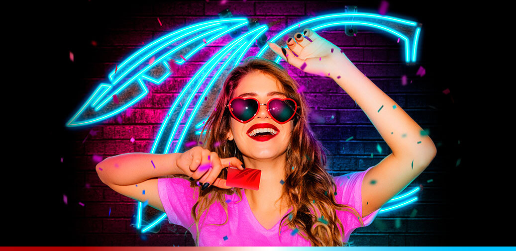 Woman wearing sunglasses and holding a rewards card in front of a neon feather design.