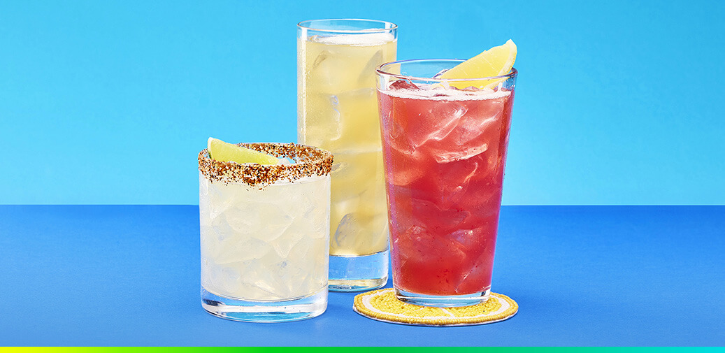 Three iced cocktails in glasses against a gradient background.
