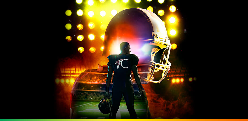 Football player standing beneath stadium lights with a large helmet in the background.